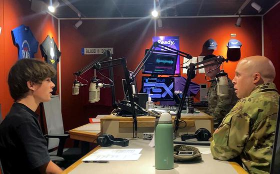 Cole Mitchell and Brittin David sit in front of microphones in the AFN radio studio.