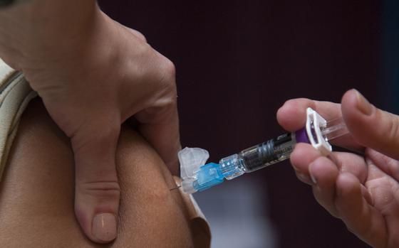 A hand presses down a syringe to give a flu shot.