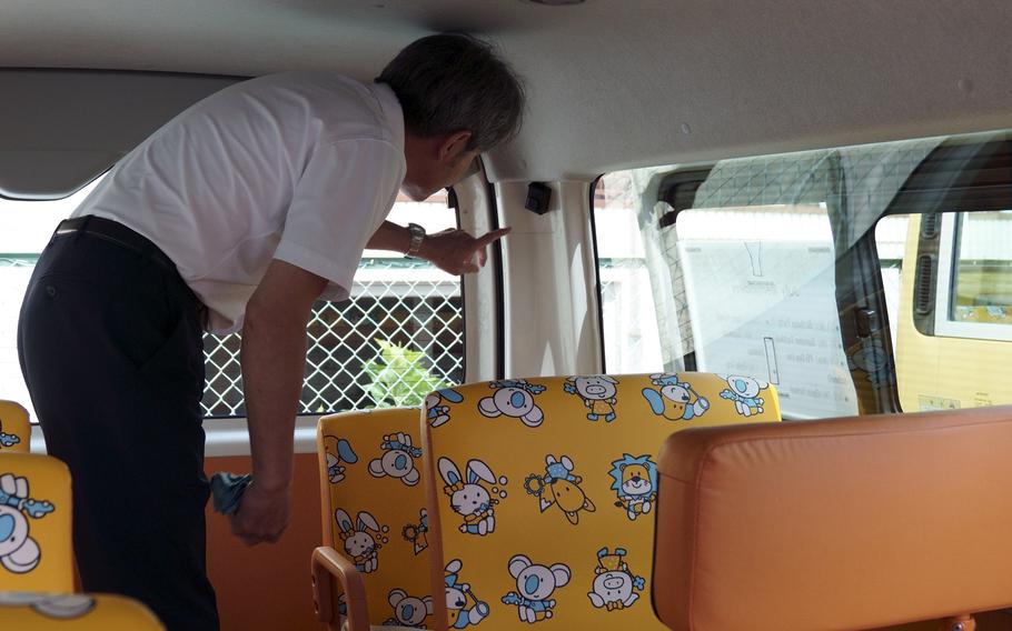 A driver for Global Step Academy, an international school near Yokota Air Base in western Tokyo, points out a safety device that prevents students from being left behind on buses, July 20, 2023. 