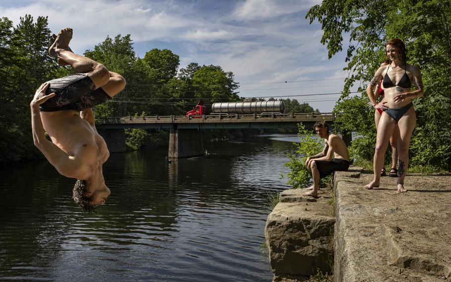 Levi Rush does a backflip off an old bridge abutment into the Saco River in Buxton, Maine, Tuesday, June 18, 2024. Hot weather is predicted until the end of the week.