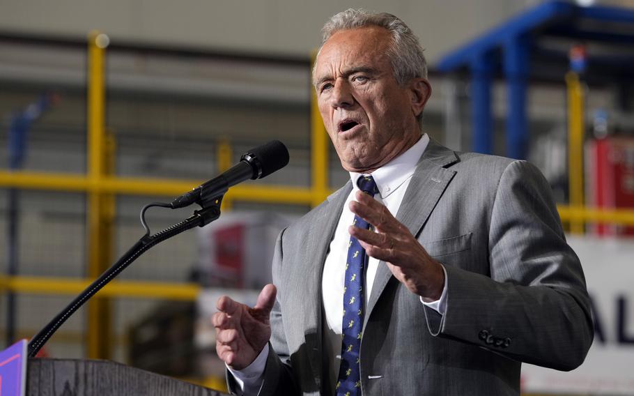 Robert F. Kennedy Jr. gestures with his hands while standing at a podium and speaking into a microphone.