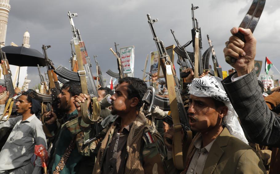 Houthi militants raise machine guns into the air during a rally.