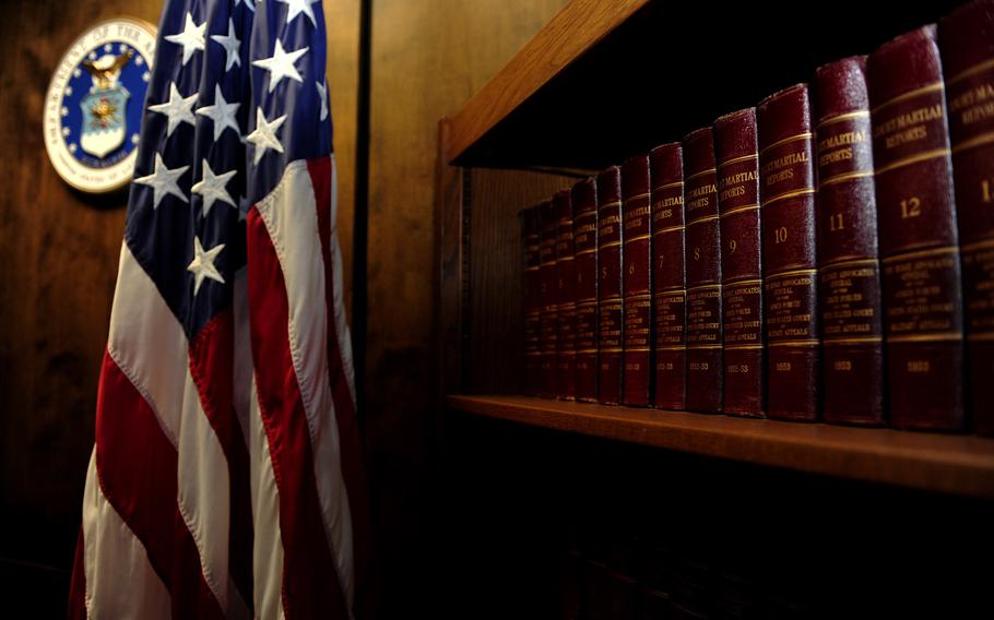 Legal books line a bookshelf in a courtroom next to the American flag