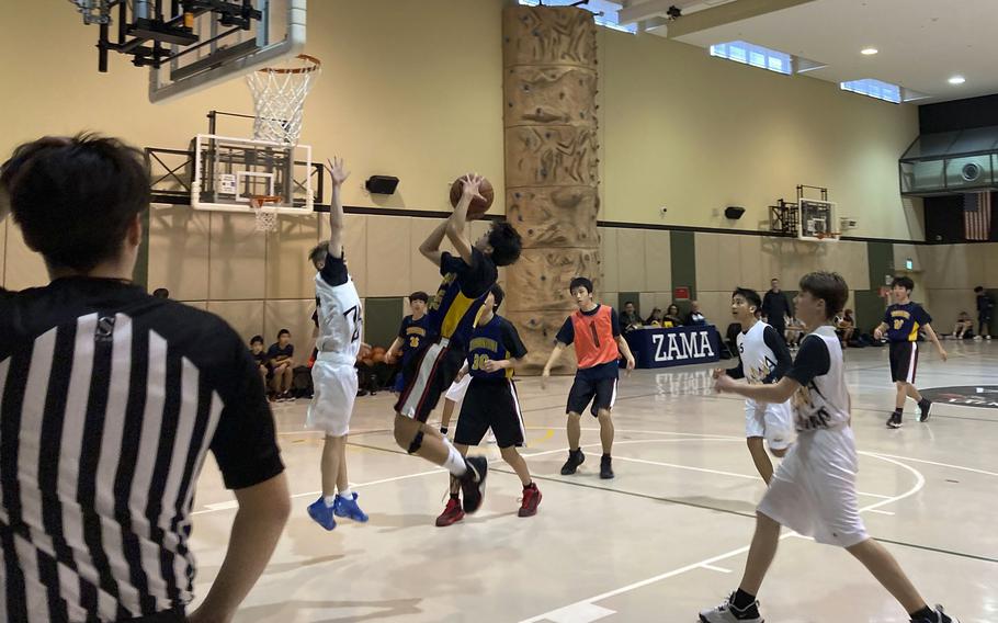 A A referee watches as a student takes a jumpshot. 