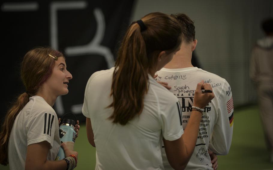 Vicenza athletes Ava Parker, left, and Sarah McGovern pen their autograph on a fellow student's tournament t-shirt during the DODEA European tennis championships at T2 Sports Health Club in Wiesbaden, Germany, on Oct. 21, 2023.