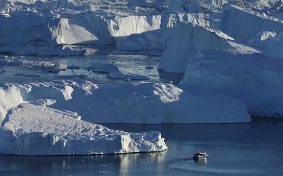 Icebergs take up most of the image while a small tugboat is seen in the bottom left quadrant.