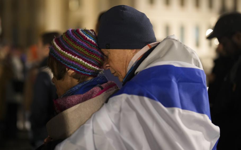 A man embraces a women at they attend a vigil for victims of the Hamas attack on Israel, during a commemoration at the Brandenburg Gate in Berlin.