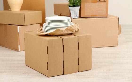 Moving boxes on the floor in empty room with a stack of plates on top of boxes in the center