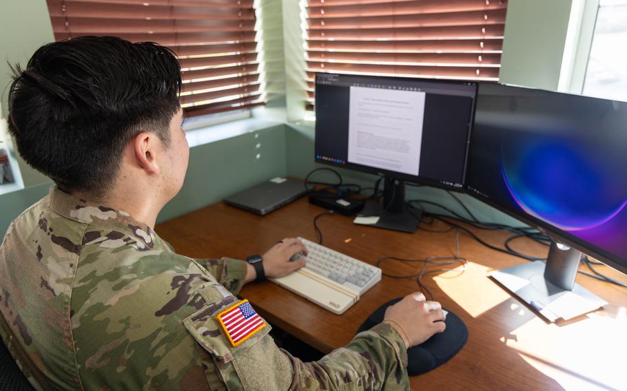 Soldier sits at a desk working on a computer.