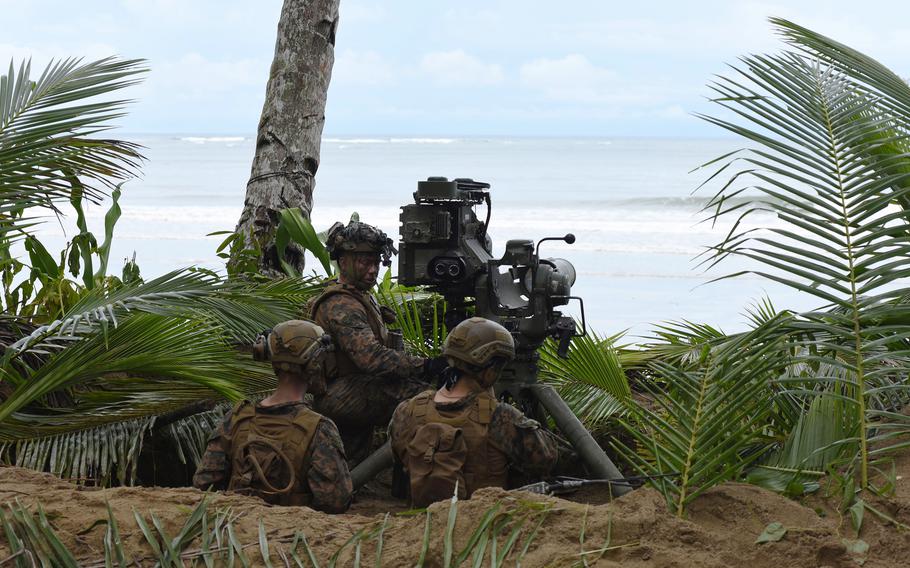 Marines in training gear stand near a missile launcher.