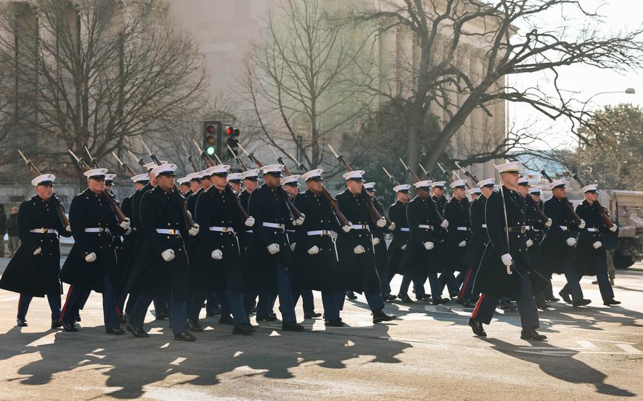 Troops with rifles on their shoulders march.