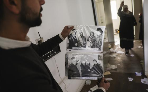 FILE.- A man shows old pictures of the late Syrian President Hafez Assad as civilians ransack the private residence of overthrown President Bashar Assad in the Malkeh district of Damascus, Syria, on Sunday, Dec. 8, 2024. (AP Photo/Ghaith Alsayed,File)