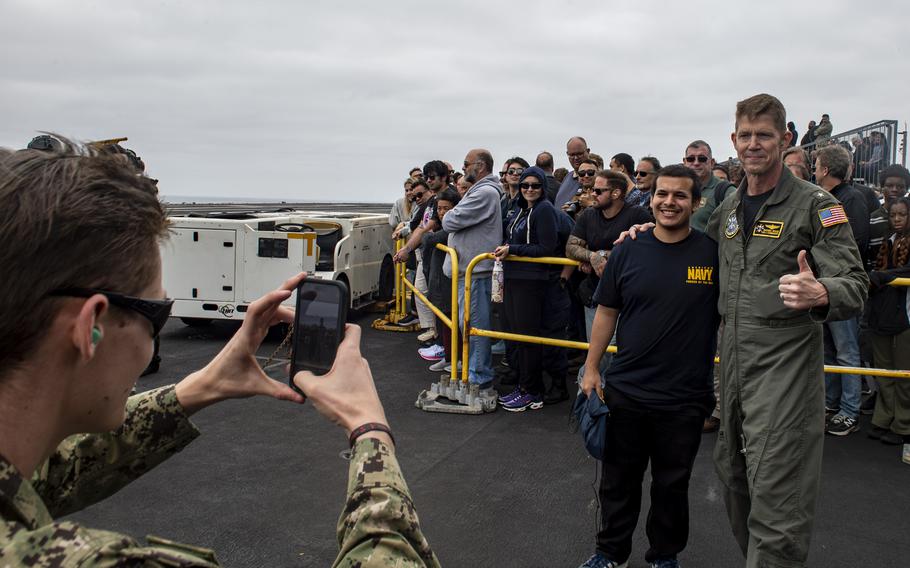 Rear Adm. Michael Wosje, commander of Carrier Strike Group One, takes a photo with a visitor aboard Nimitz-class aircraft carrier USS Carl Vinson while underway for a Family and Friends Day Cruise on Saturday, Aug. 17, 2024.