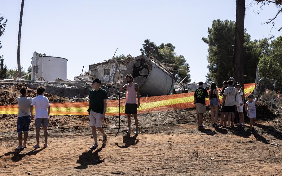 People walk past a building that was destroyed by Iran’s missile barrage on Israel, Oct. 3, 2024.