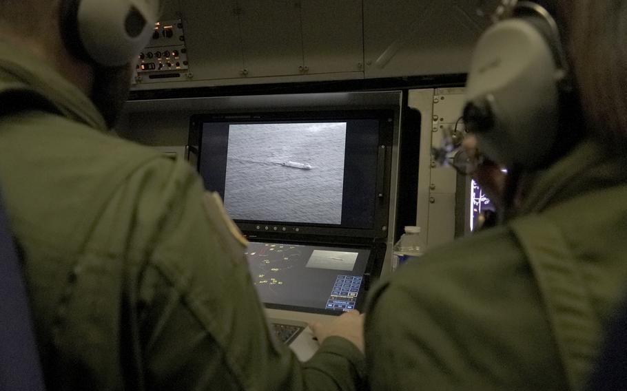 Two French sailors wearing headphones watch screens showing images from cameras pointed at the Baltic.