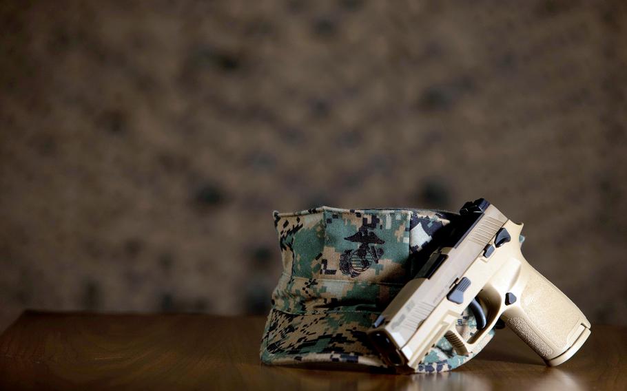 A handgun leaning on a Marine Corps utility cap.