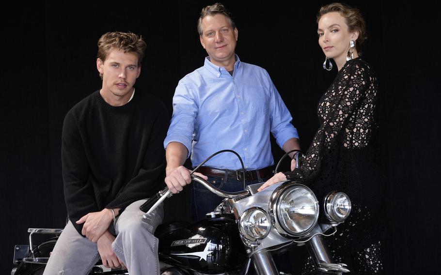 Jeff Nichols, center, writer and director of “The Bikeriders,” poses with cast members Austin Butler, left, and Jodie Comer, May 30, in Los Angeles. The motorcycle is a 1965 Harley Davidson Pan Head that Butler rode in the film. 