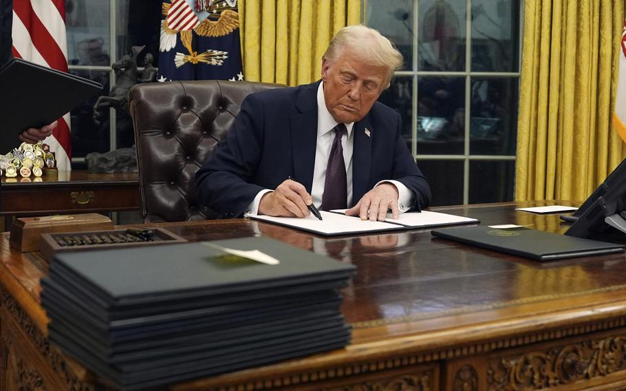 Donald Trump signs an execuitve order at his desk in the Oval Office of the White House.