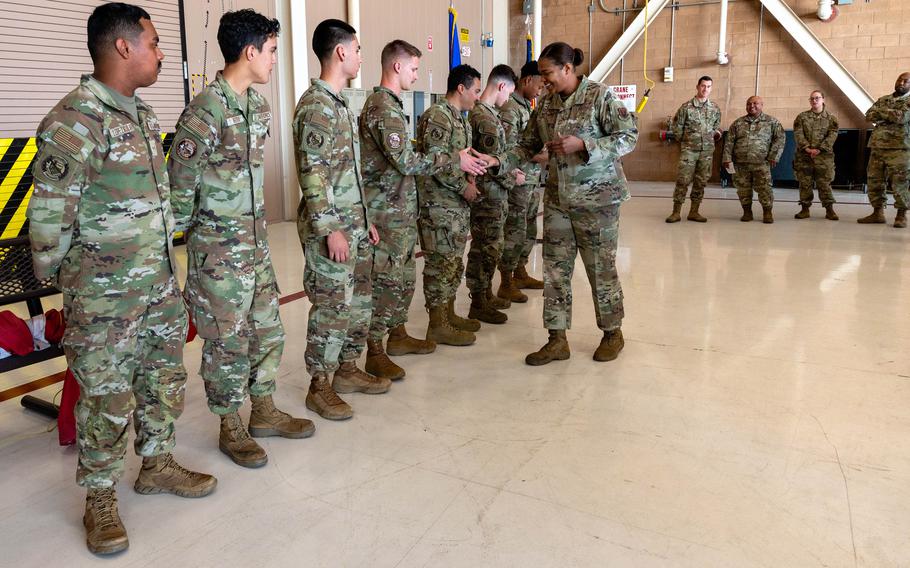 Chief Master Sgt. Adrienne Warren, 99th Air Base Wing command chief master sergeant, distributes coins to Airmen who helped rescue hikers from a flash flood in Zion National Park in Utah, Aug. 26, 2024, at Nellis Air Force Base, Nevada.