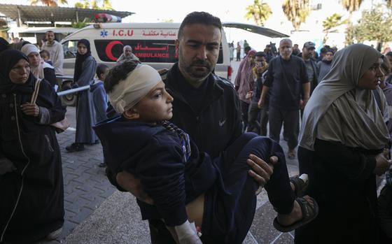 A Palestinian man carries a wounded child, following an Israeli bombardment in Nuseirat, central Gaza, as they arrive at the Al-Aqsa Martyrs hospital in Deir al-Balah, Gaza Strip Wednesday, Dec. 4, 2024. (AP Photo/Abdel Kareem Hana)