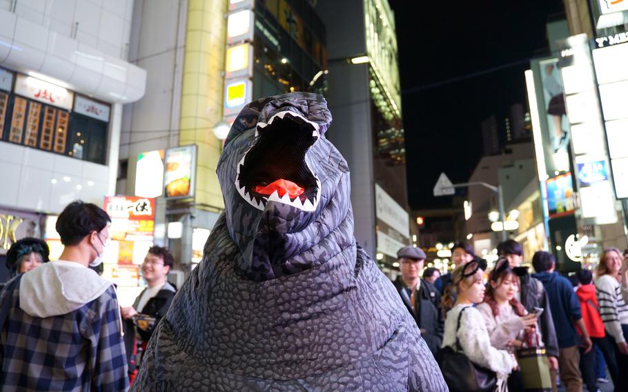 A Halloween reveler in a Godzilla costume poses on a street in Tokyo's Shibuya ward, Tuesday, Oct. 31, 2023.  