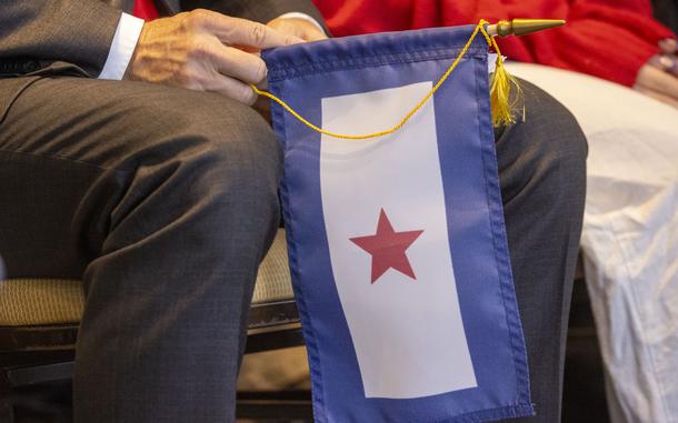 A flag with a blue border and red star is seen between the legs of a seated person.