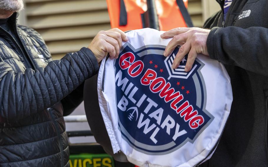 Hands pull down a sign on a yardage marker.