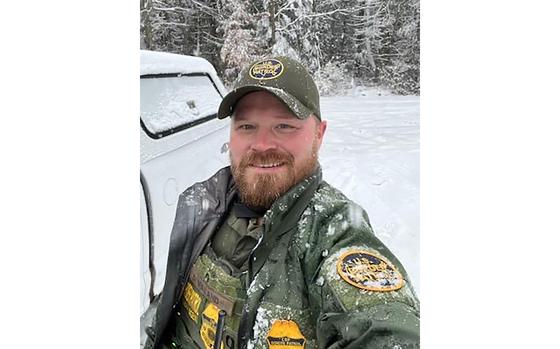 A man takes a selfie in his border patrol uniform while standing outside in the snow.