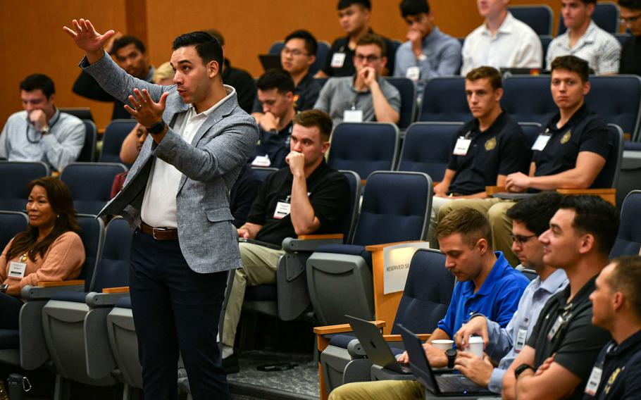 An instructor in a blazer gray blazer speaks to U.S. Military Academy cadets in an auditorium.