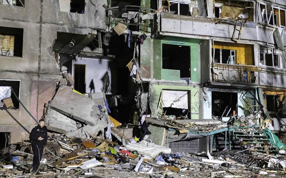 A police officer walks past the facade of a building destroyed by an airstrike.