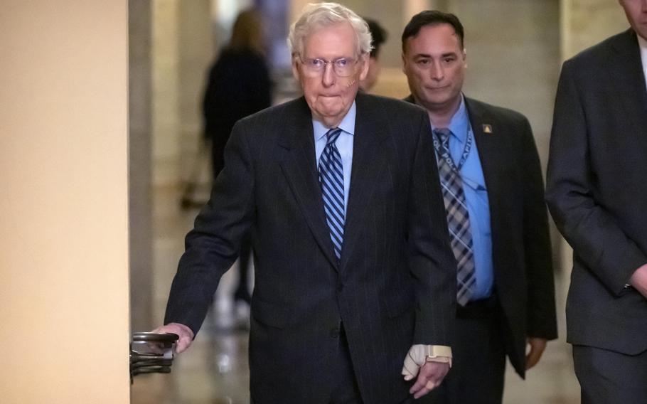 Senate Minority Leader Mitch McConnell of Ky., left, wears a bandage on his face and wrist as he walks to cast a vote on the Senate floor after falling during a luncheon on Capitol Hill, Tuesday, Dec. 10, 2024, in Washington.