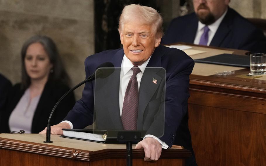 Donald Trump, standing behind a teleprompter at podium on the dais on the floor of the Capitol, smiles as he speaks into a microphone.