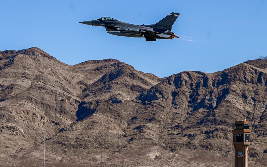 An aircraft flies over brown mountains