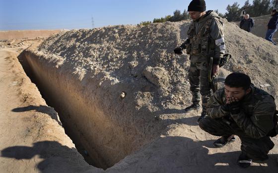 Syrian fighters from rebel group, observe a location identified as a mass grave for detainees killed under rule of Bashar Assad in Najha, south of Damascusn Najha, south of Damascus, Syria, Tuesday, Dec. 17, 2024. (AP Photo/Hussein Malla)