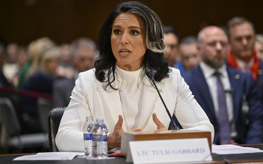 Tulsi Gabbard in a white suit, with her hands gesturing while remaining at her table.