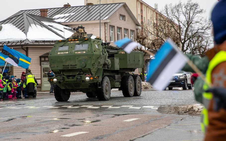 A HIMARS rolls down the street with Estonian flags waving.