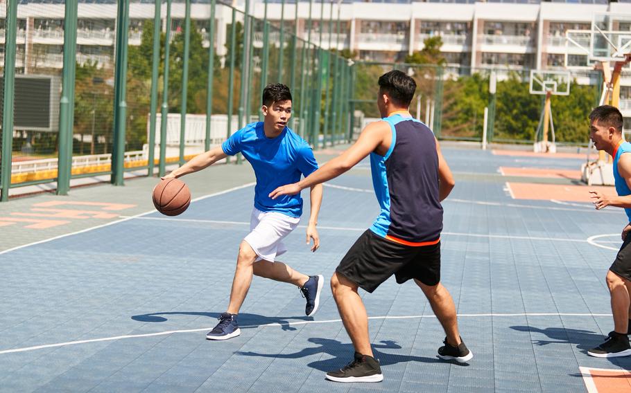 Young adults playing basketball on a basketball court