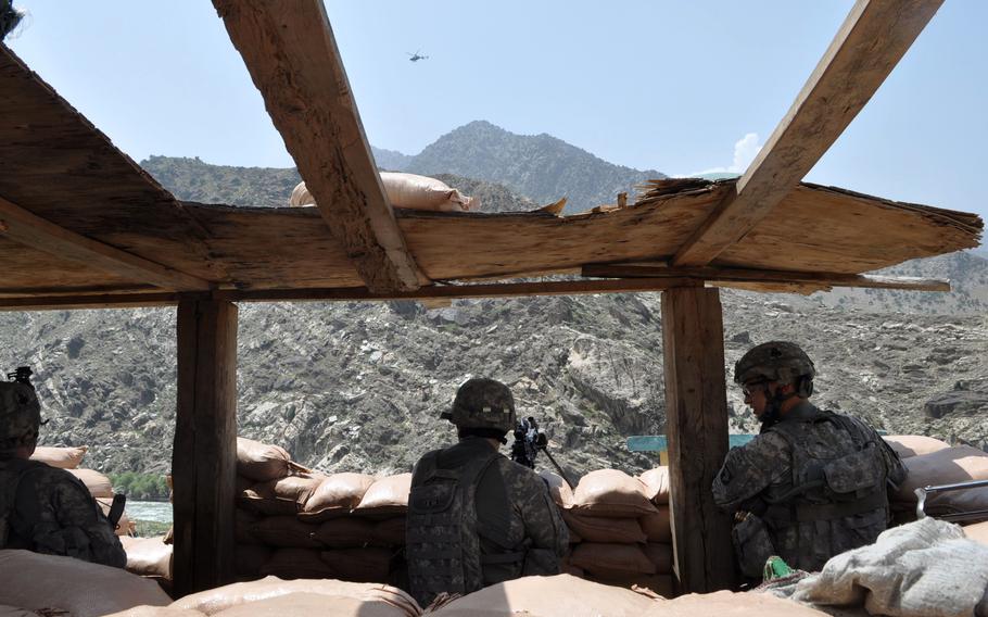 Soldiers take in the view at the guard post of the Afghan National Police station at Tantil Village in Pech River Valley of Kunar province.