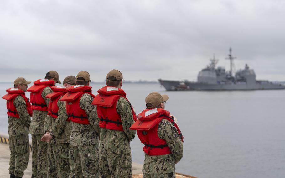 A formation of sailors stand by to assist the guided-missile cruiser USS Leyte Gulf as it returns to Naval Station Norfolk on May 17, 2024, after its final deployment.