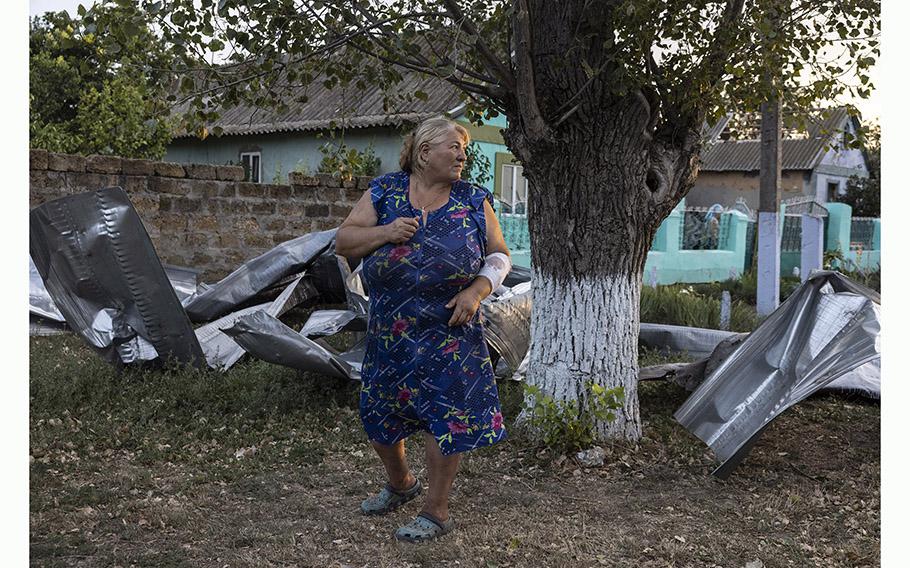 Tetiana Lazarova, 52, stands among twisted pieces of aluminum that littered yards in the Ukrainian village of Pavlivka after the grain storage facility was hit by Russian missiles. 