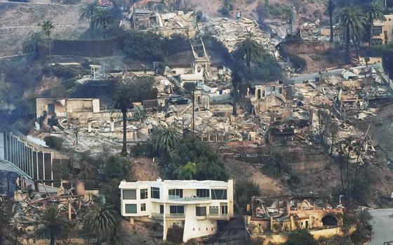 The remains of large homes on a hill are seen from above, with one home alone intact.