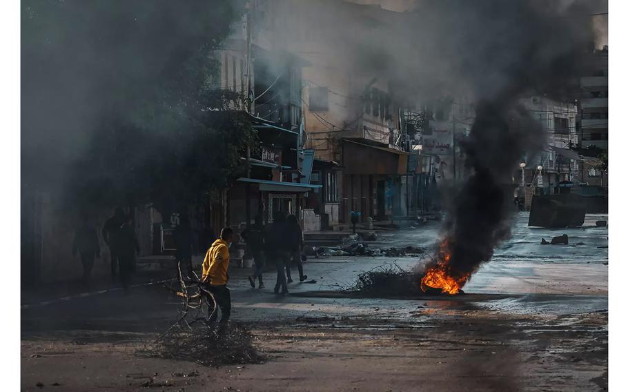 Young men place obstacles to try to block Israeli army vehicles from cruising through a street during Israeli raids in Jenin, in the West Bank, and its refugee camp in December 2023.