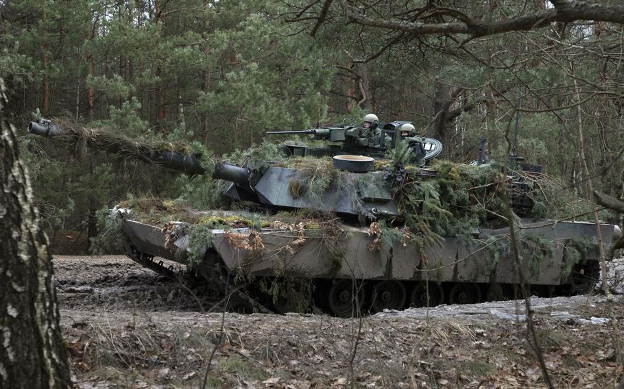 A Polish M1 Abrams tank traverses muddy terrain