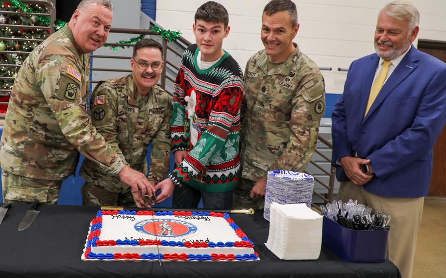 Five members of the Army National Guard and Tennessee National Guard, four older and one younger, cut a service birthday cake.