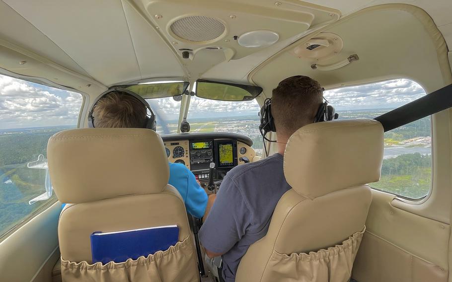 Two people in the pilot seats of a small plane, seen from behind the seats.