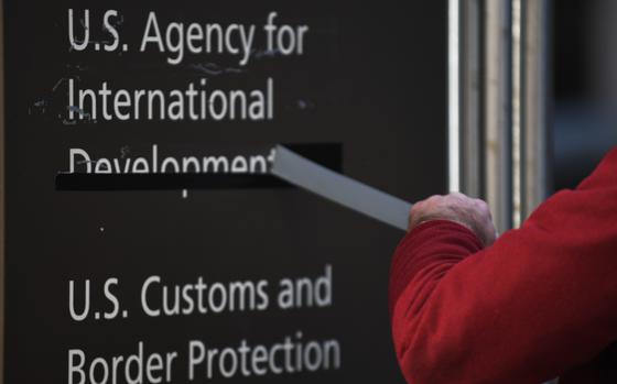 A man pulls away tape covering the name of the U.S. Agency for International Development in Washington on Feb. 7. MUST CREDIT: Astrid Riecken/For The Washington Post