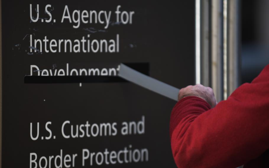 A man pulls away tape covering the name of the U.S. Agency for International Development in Washington on Feb. 7. 