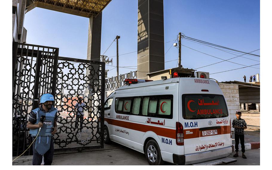 A journalist stands by as Palestinian health ministry ambulances cross the gate to enter the Rafah border crossing in the southern Gaza Strip before crossing into Egypt on Nov. 1, 2023. 