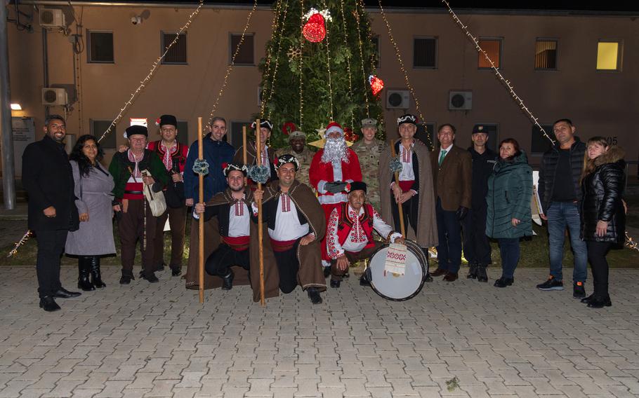 A crowd, including Santa, poses in front of a Christmas tree.