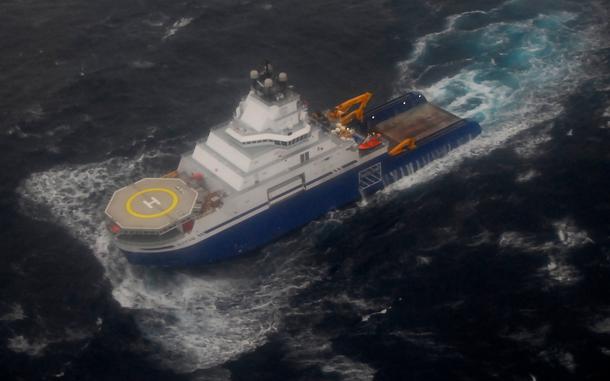 A tow supply vessel, seen from above, travels through open water.